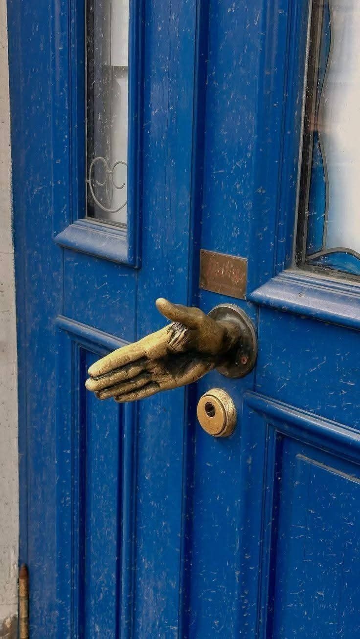 Hand-shaped door knocker on blue door