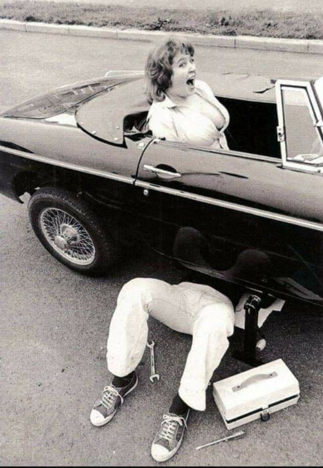 Woman in Fur Coat Inspecting Car Undercarriage