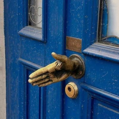 Hand-shaped door knocker on blue door