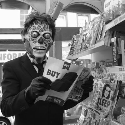 Masked figure reading 'BUY' magazine mask skull suit magazine bookstore